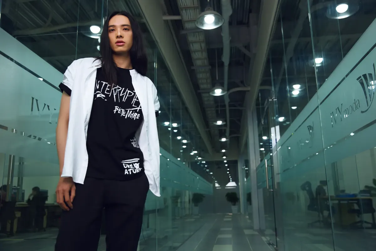 Stylish person poses in sleek office hallway, showcasing urban fashion.