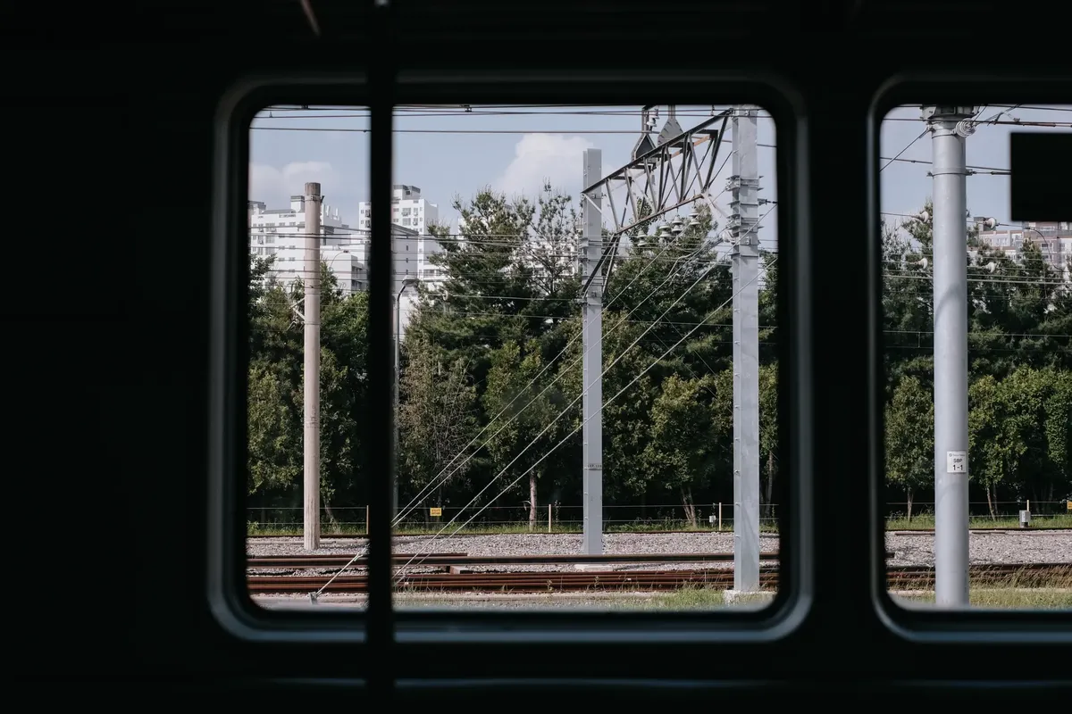 Urban view captured from a train window in Chuncheon, showcasing tracks and city buildings.