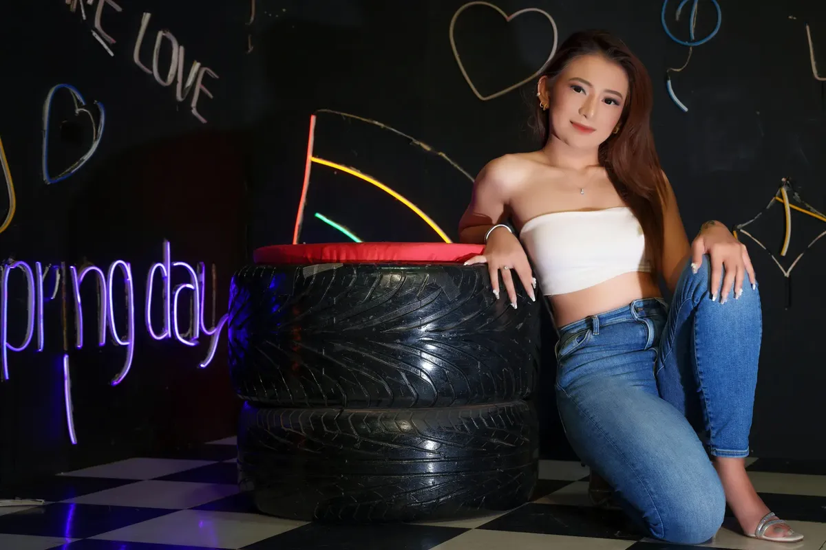 Trendy young woman in a stylish studio with neon signs and checkered floor.