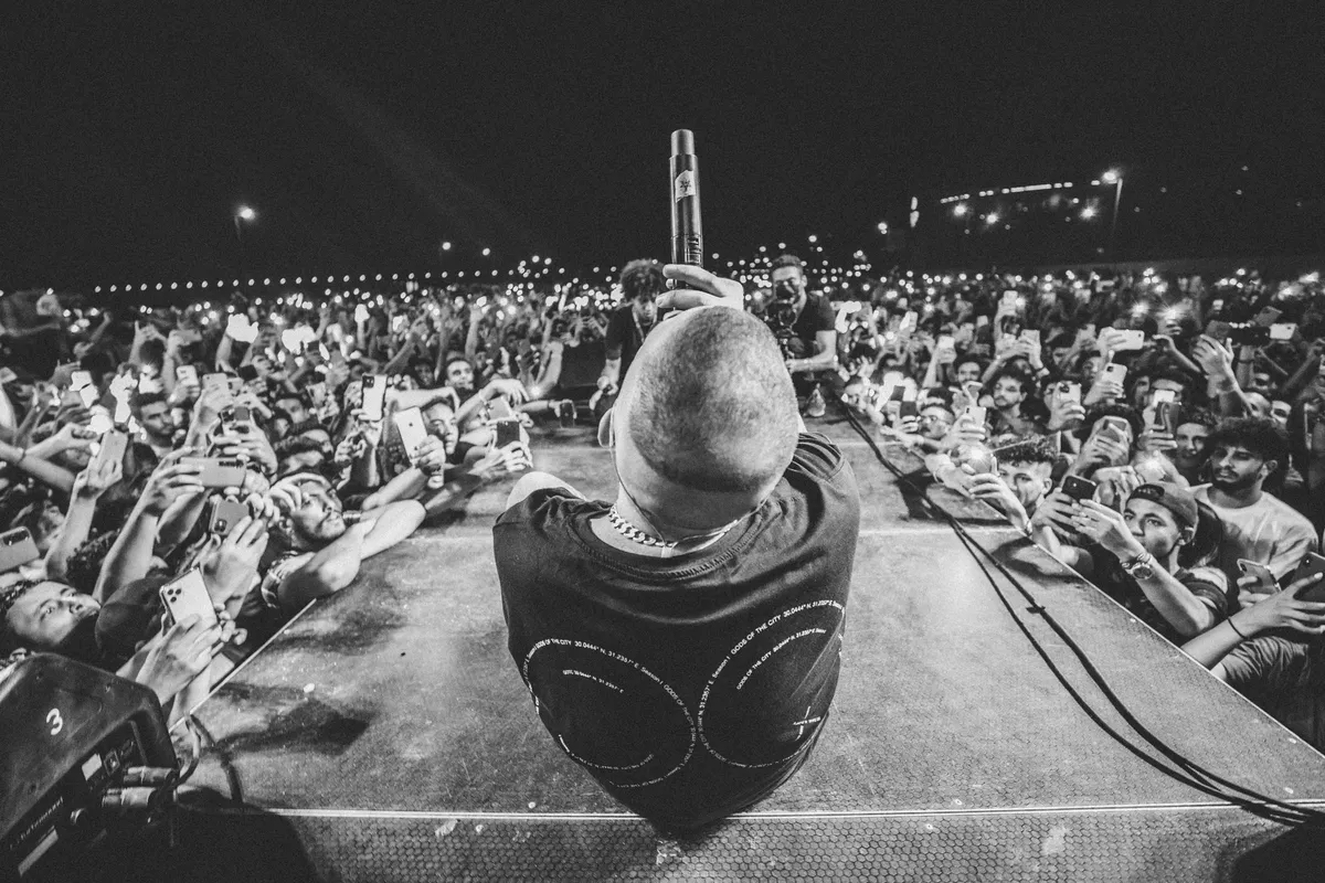 Black-and-white photo capturing a dynamic live concert with singer on stage and enthusiastic crowd.