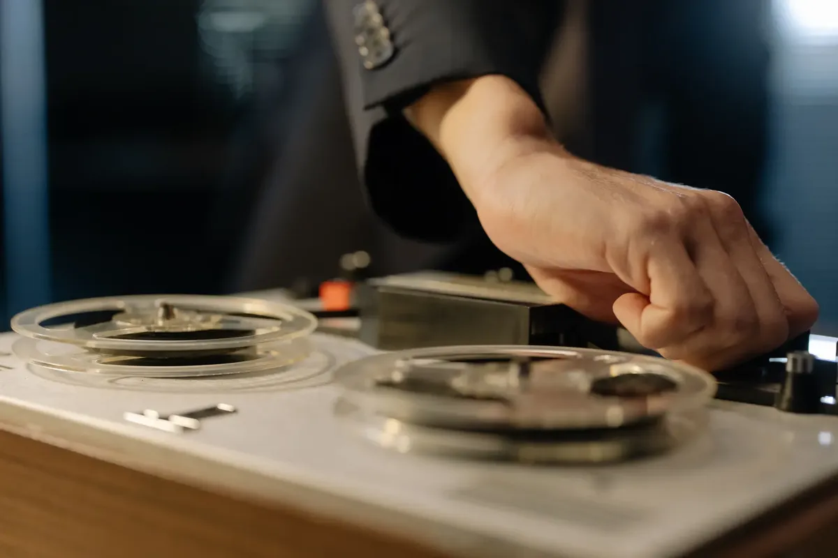 A close-up shot of a hand adjusting controls on a vintage reel-to-reel tape recorder.