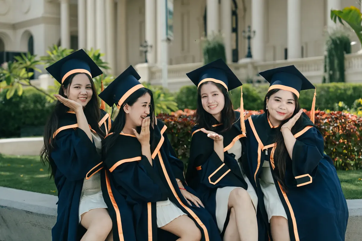 Group of young women celebrating graduation in caps and gowns outdoors.